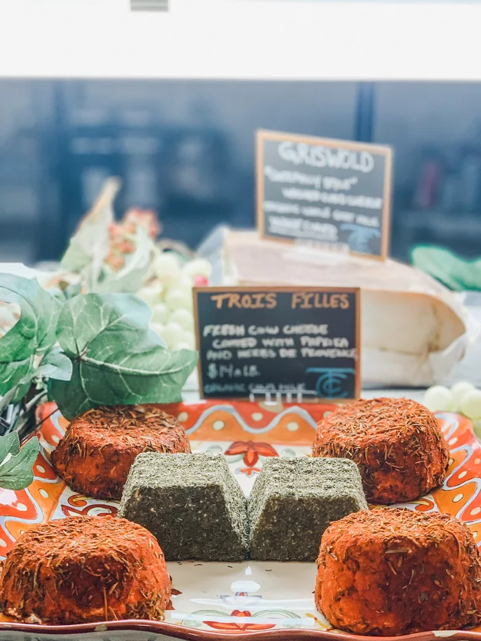 A market stall with two round loaves on a patterned cloth and hand-written signs behind.